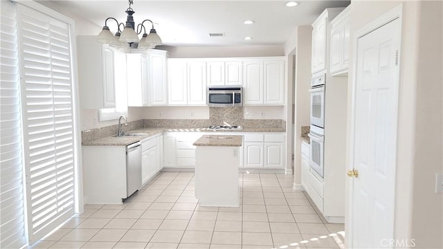 kitchen featuring light tile patterned floors, stainless steel appliances, a sink, visible vents, and white cabinetry