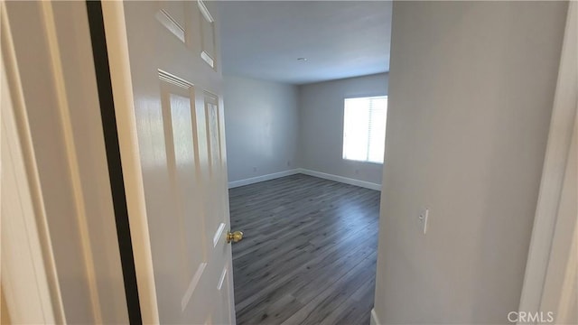 unfurnished room featuring baseboards and dark wood-type flooring