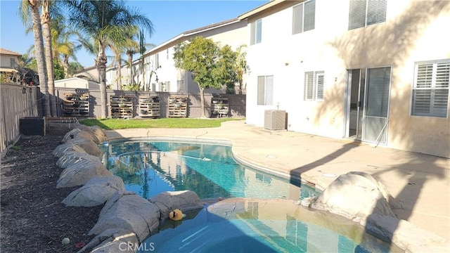 view of pool featuring a patio area, a fenced backyard, a pool with connected hot tub, and cooling unit