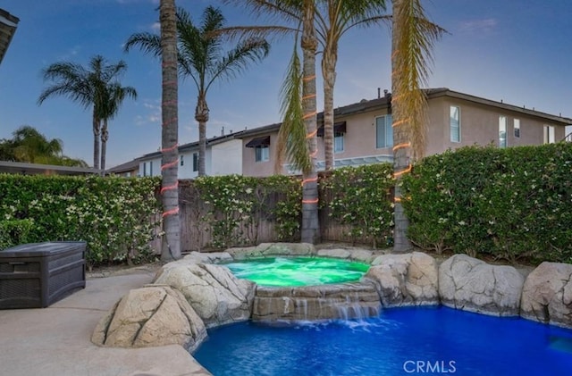 view of swimming pool with a fenced in pool and an in ground hot tub