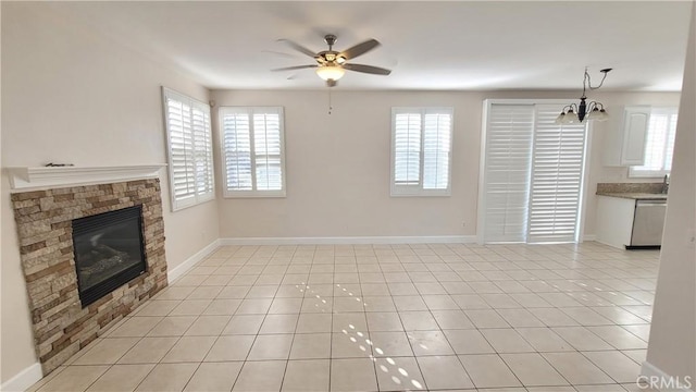 unfurnished living room featuring baseboards, a stone fireplace, light tile patterned flooring, and a healthy amount of sunlight