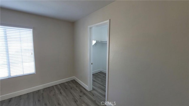 interior space featuring a walk in closet, a closet, light wood-style flooring, and baseboards