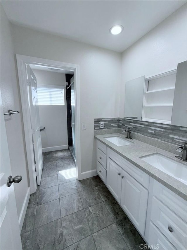 full bathroom with a sink, backsplash, baseboards, and double vanity