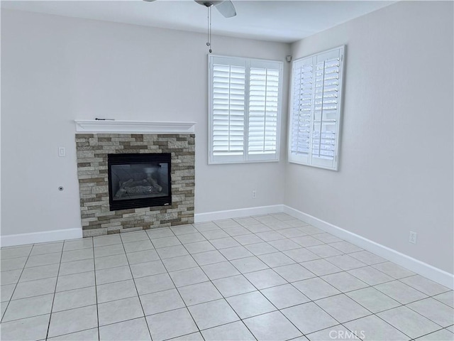 unfurnished living room featuring a glass covered fireplace, ceiling fan, and baseboards