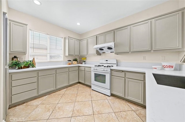 kitchen featuring recessed lighting, gray cabinets, light countertops, white range with gas stovetop, and under cabinet range hood