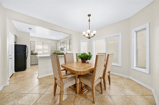 dining area with light tile patterned floors, a notable chandelier, visible vents, and baseboards