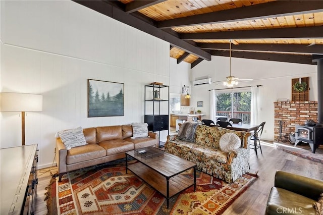 24950 Roble Dr, Idyllwild, CA 92549 - living area with beam ceiling, wood ceiling, a wood stove, wood finished floors, and a wall mounted air conditioner