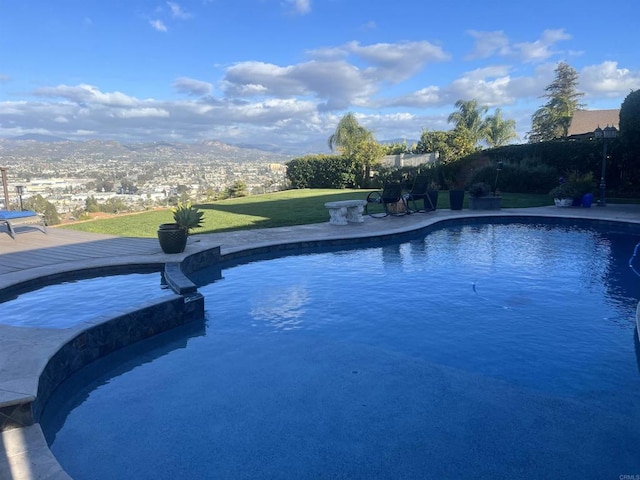 view of pool with a lawn and a pool with connected hot tub