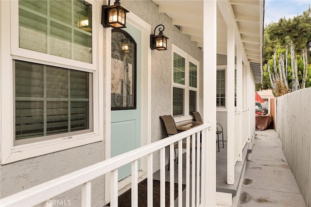 property entrance with covered porch and fence