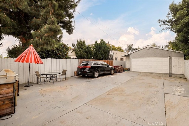 view of vehicle parking featuring a garage and fence