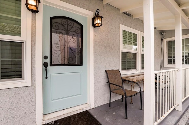 entrance to property featuring covered porch and stucco siding