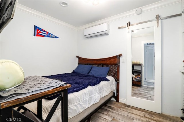 bedroom with a barn door, wood finish floors, a wall unit AC, and crown molding