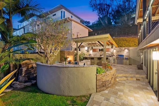 view of patio / terrace with a lit fireplace, an outdoor kitchen, and area for grilling