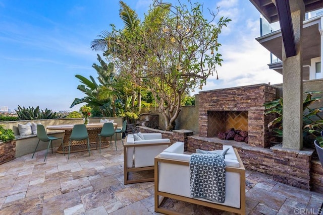 view of patio with fence, an outdoor stone fireplace, and outdoor dining area