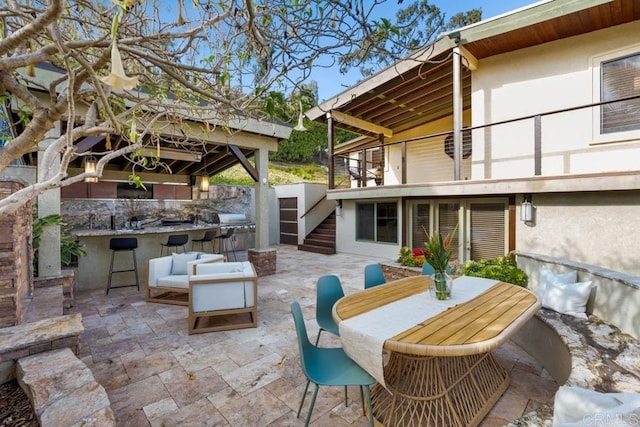 view of patio with outdoor dry bar, outdoor dining space, and stairs