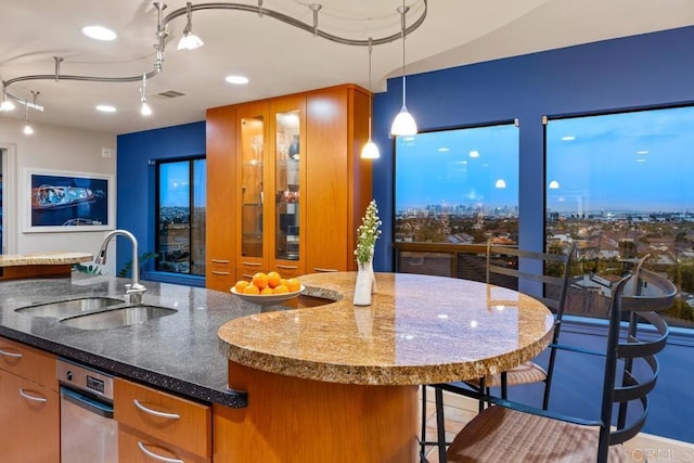 kitchen with brown cabinetry, dark stone countertops, a sink, and visible vents