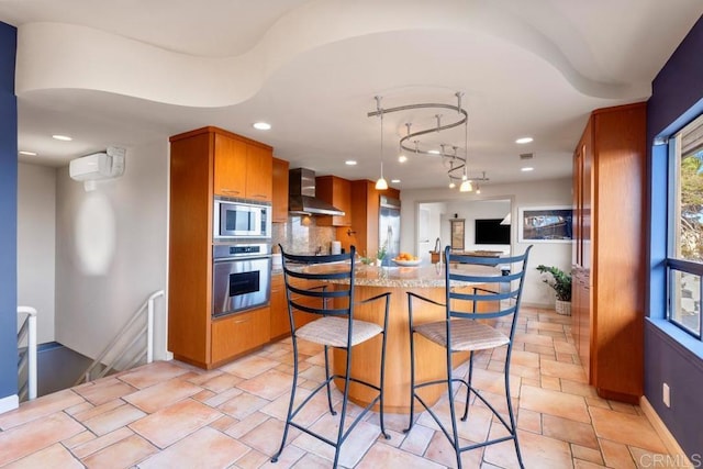 kitchen featuring decorative backsplash, wall chimney exhaust hood, a breakfast bar area, brown cabinets, and stainless steel appliances