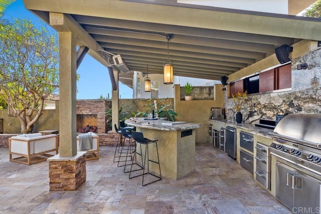 view of patio / terrace featuring an outdoor brick fireplace, grilling area, fence, exterior kitchen, and outdoor wet bar