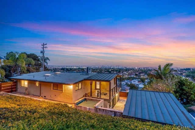 back of property at dusk featuring a standing seam roof, metal roof, and stucco siding