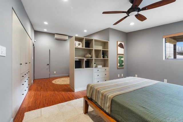 bedroom with a wall mounted AC, ceiling fan, wood finished floors, and recessed lighting