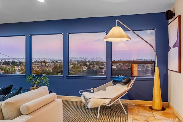 sitting room with baseboards, stone finish flooring, and a city view