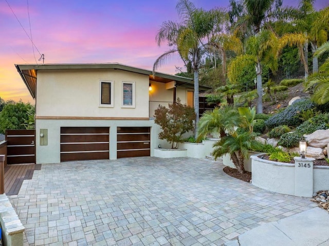 view of front facade featuring a garage, decorative driveway, and stucco siding