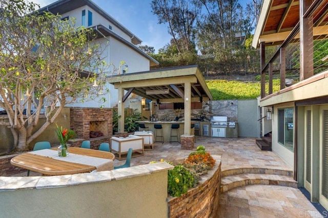 view of patio with outdoor dry bar, an outdoor stone fireplace, area for grilling, and a grill