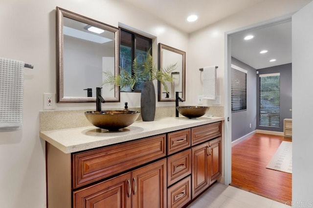 bathroom featuring double vanity, a sink, and recessed lighting