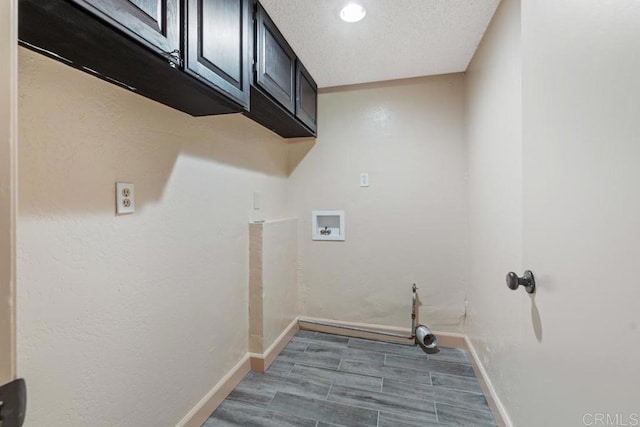 laundry area featuring wood finish floors, hookup for a washing machine, cabinet space, a textured ceiling, and baseboards