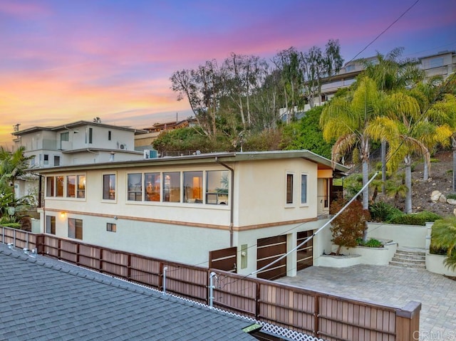 back of property featuring a garage, a patio, and stucco siding