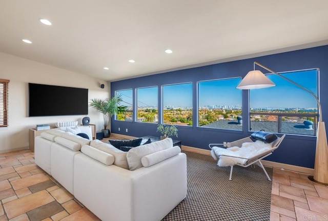 living area with lofted ceiling, baseboards, stone tile flooring, and recessed lighting