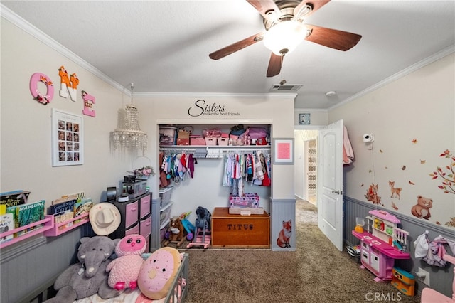 carpeted bedroom with a wainscoted wall, crown molding, visible vents, and a closet