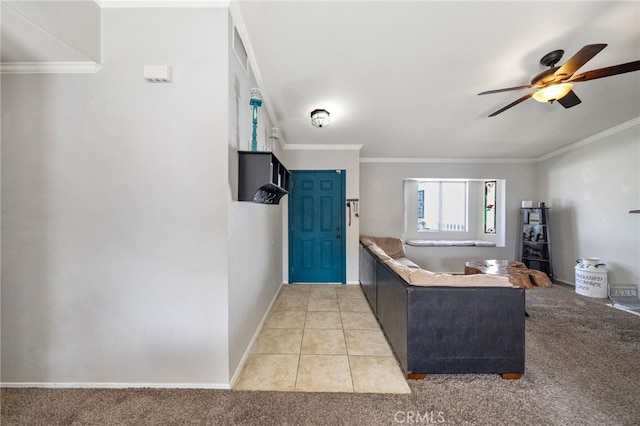 foyer featuring light tile patterned floors, ceiling fan, light colored carpet, baseboards, and crown molding