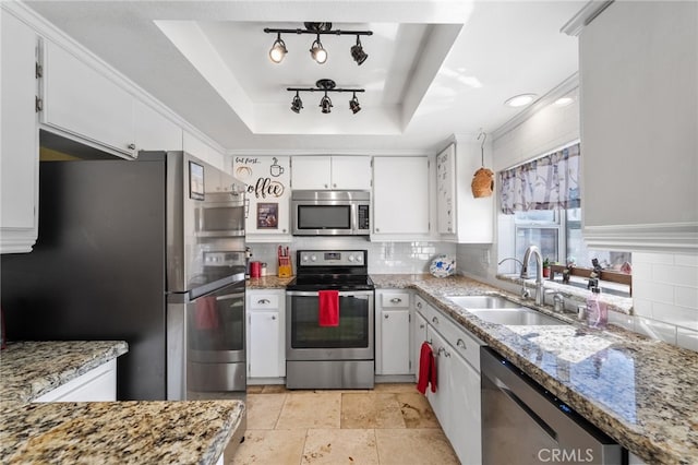 kitchen with stainless steel appliances, tasteful backsplash, a raised ceiling, white cabinets, and a sink