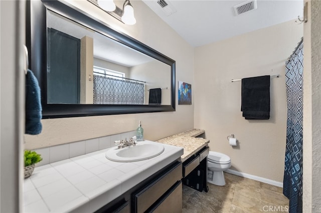 bathroom featuring toilet, vanity, visible vents, and baseboards