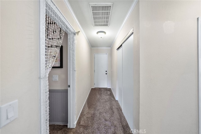 hall with carpet floors, a wainscoted wall, visible vents, and ornamental molding