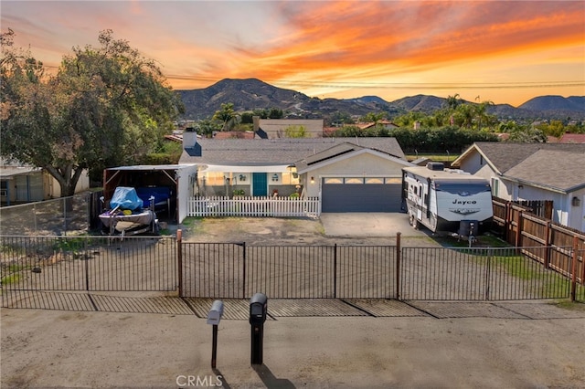 view of front of property with a fenced front yard, concrete driveway, a mountain view, and an attached garage