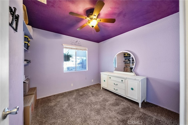 unfurnished bedroom with ceiling fan and dark colored carpet