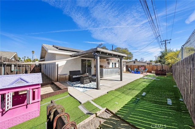 back of property featuring a fenced backyard, solar panels, a yard, stucco siding, and a patio area