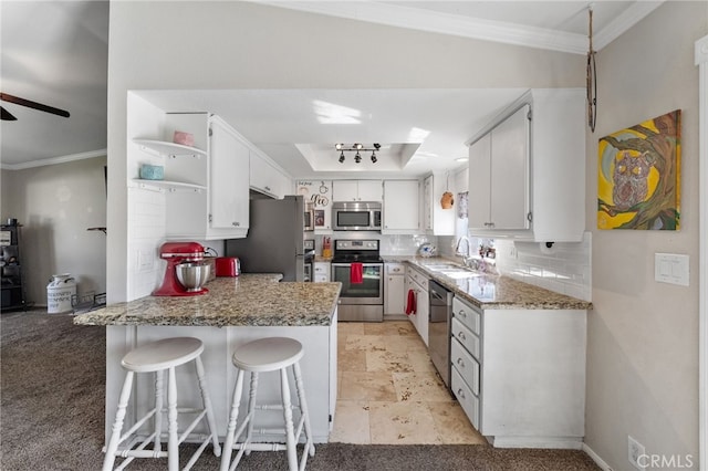 kitchen featuring tasteful backsplash, appliances with stainless steel finishes, ornamental molding, a peninsula, and a sink