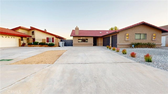 view of front of house featuring fence, driveway, a chimney, stucco siding, and a garage