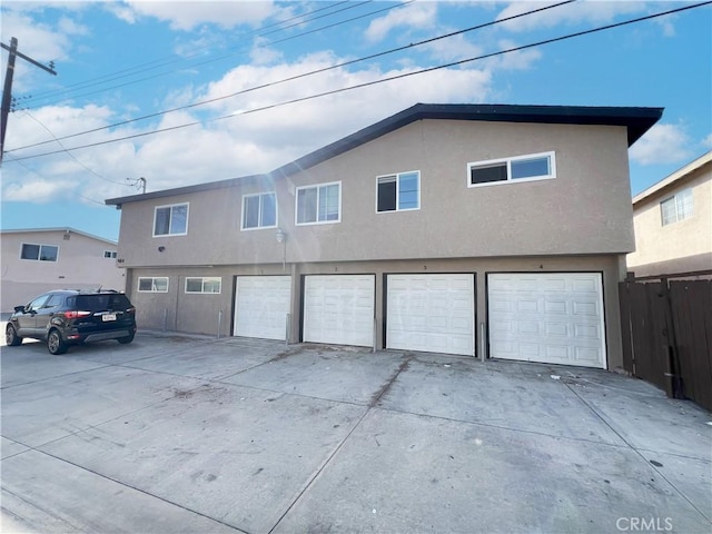 view of front of home featuring a garage, fence, and stucco siding