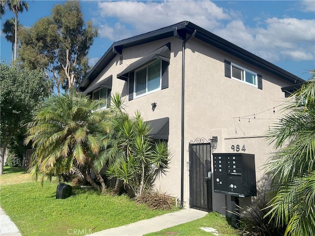 view of home's exterior featuring a yard, mail area, and stucco siding