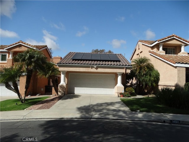 view of front of house with stucco siding, concrete driveway, roof mounted solar panels, a garage, and a tiled roof