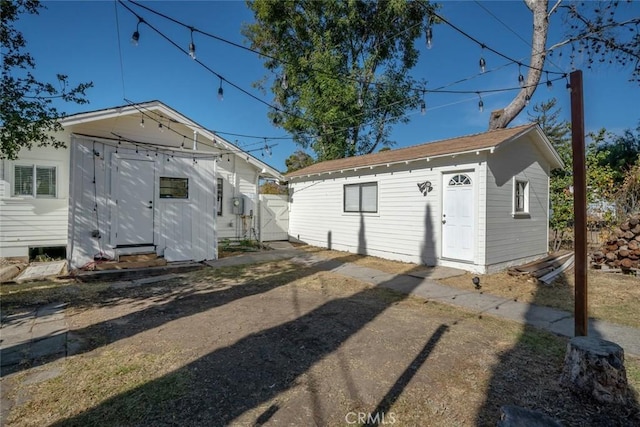 back of property featuring entry steps, a chimney, and an outbuilding