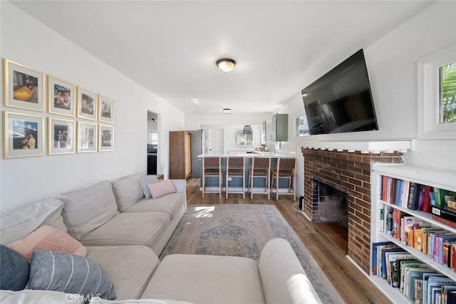 living room featuring a brick fireplace and wood finished floors