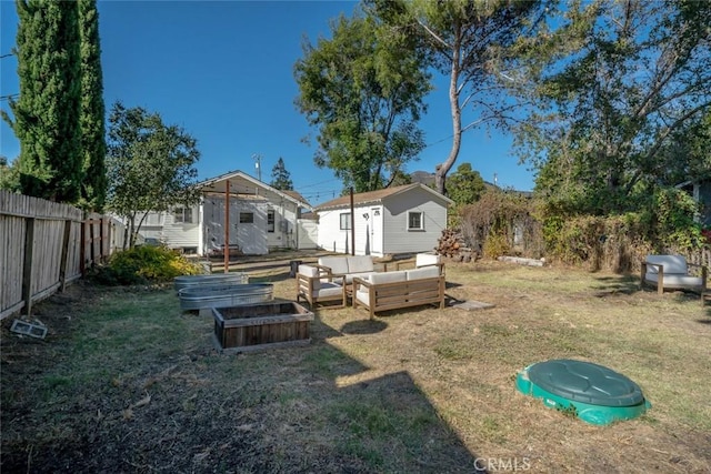 view of yard with a fenced backyard, a vegetable garden, an outdoor hangout area, and an outdoor structure