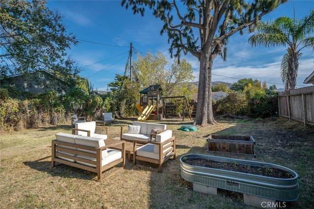 view of yard featuring a vegetable garden, a playground, fence, and an outdoor hangout area