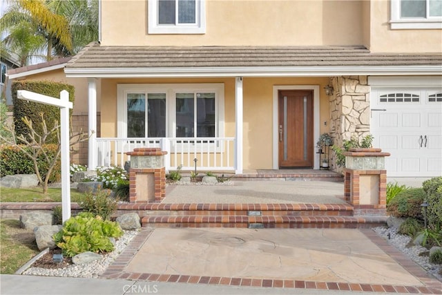 view of exterior entry featuring covered porch, stone siding, a tile roof, and stucco siding