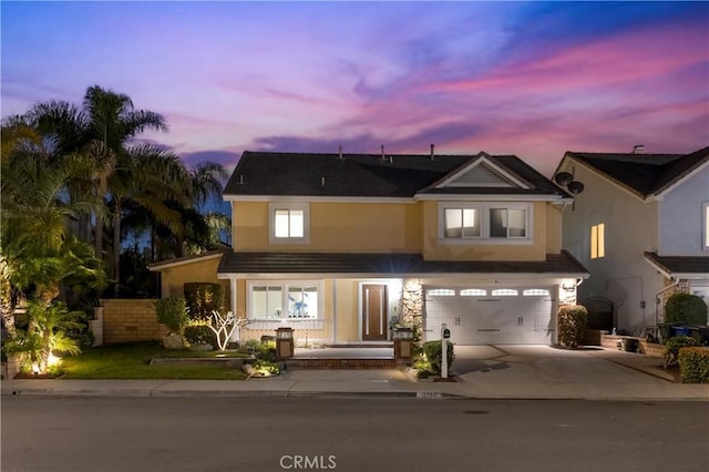 view of front of house featuring driveway, an attached garage, covered porch, fence, and stucco siding